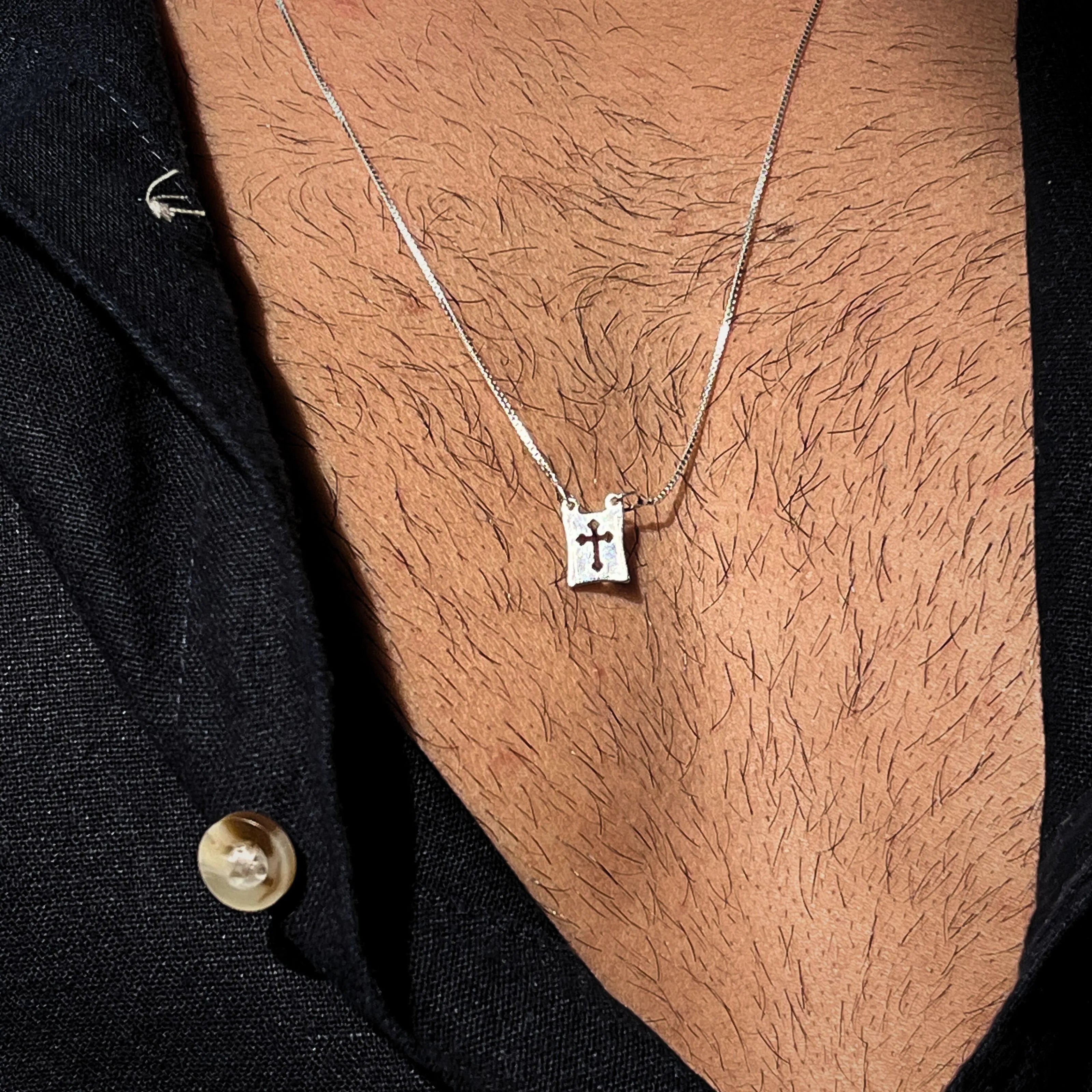 Colar masculino de prata 925 com medalha de cruz vazada, trazendo proteção espiritual e sofisticação com corrente veneziana discreta.