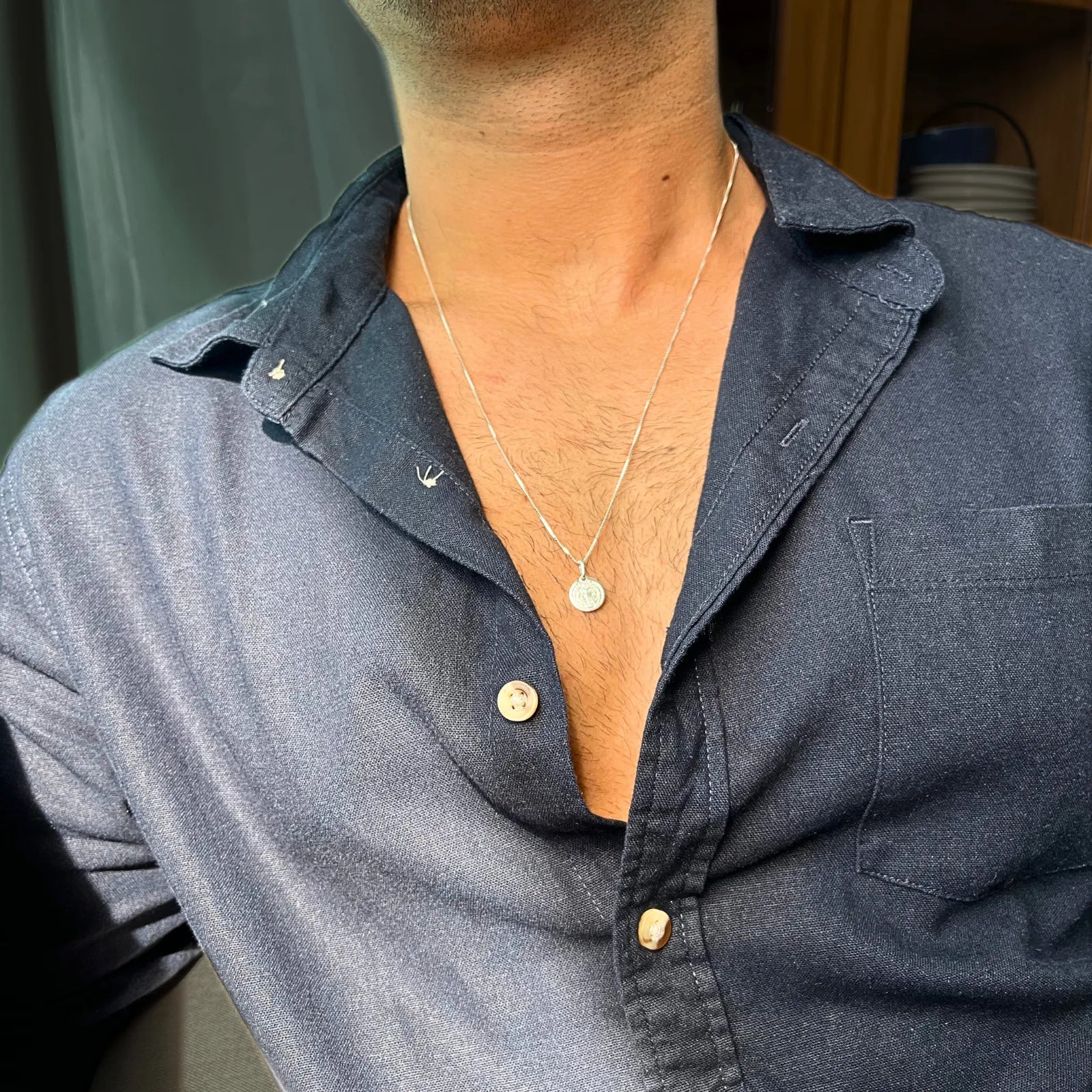 Colar Benedizione em prata 925 maciça com pingente da oração Pai Nosso, exibido em modelo masculino com camisa azul de botão
