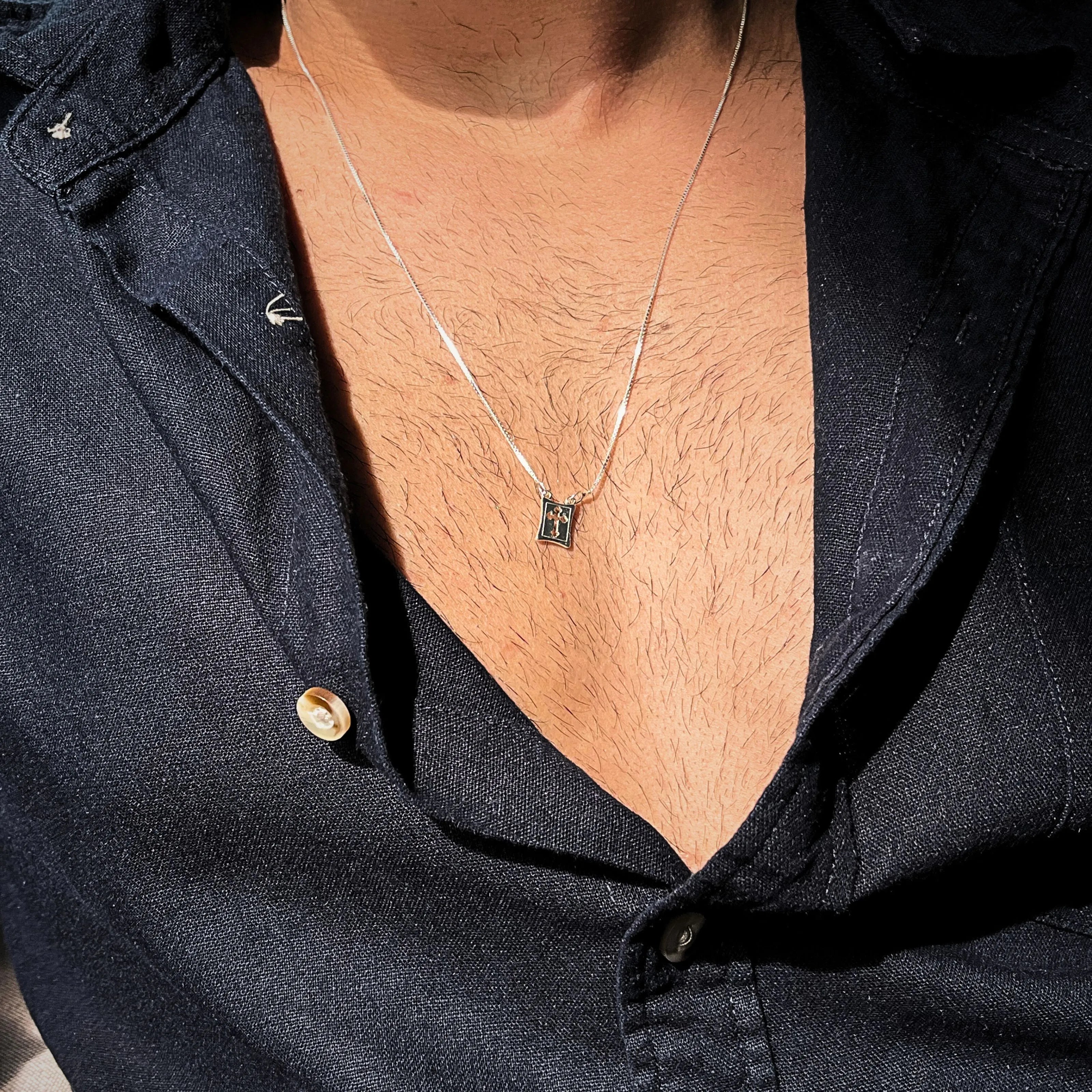 Colar masculino de prata 925 com medalha de cruz vazada em uso, representando fé, proteção e estilo discreto. Corrente veneziana de alta qualidade.